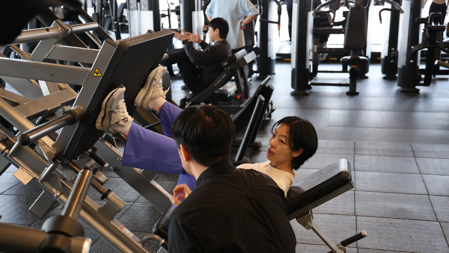트레이너가 회원의 자세를 살피며 일대일 코칭하는 모습